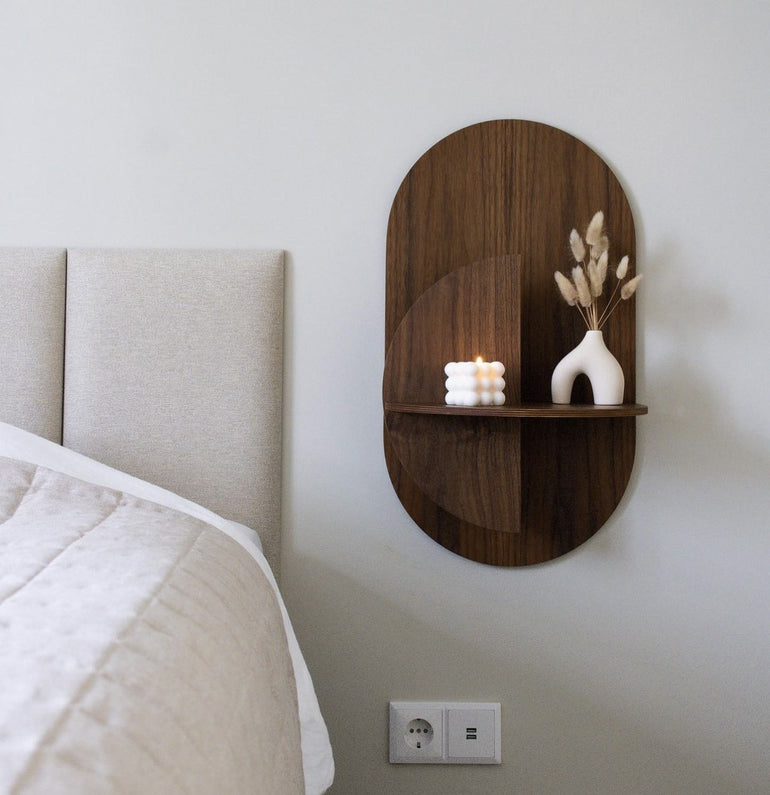 Alba Slim floating bedside table in walnut beside a bed, styled with a vase and candle.