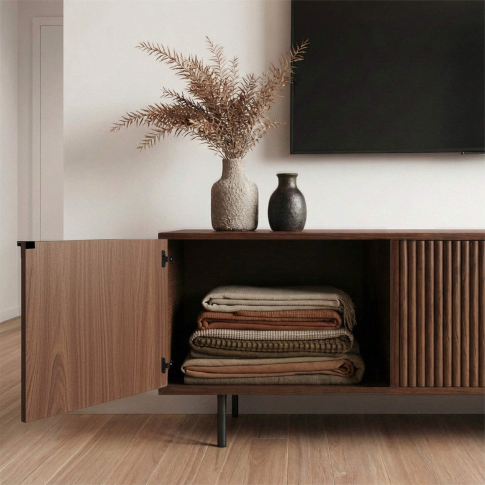 Open door of a walnut-toned Pau TV unit showing folded blankets inside