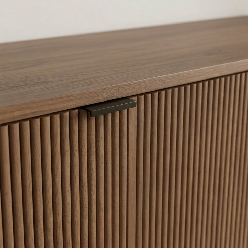 Close-up of a black handle above the walnut-toned textured front of Pau