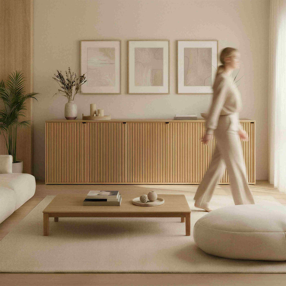 Person walking past a long oak-toned Pau sideboard with textured doors in a living room