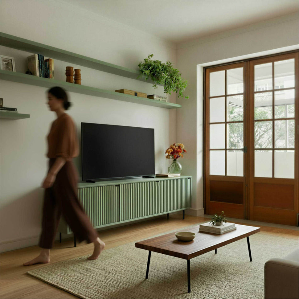 Person walking past a pale green Pau TV unit with textured doors