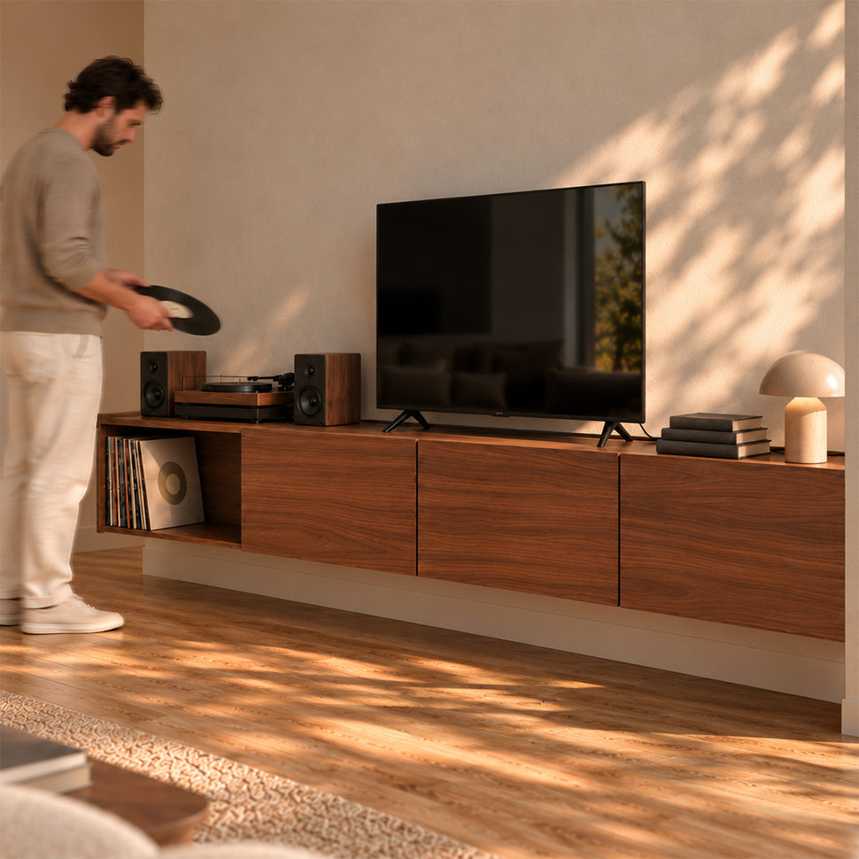 Person holding a record beside a four-module Dalea XL walnut-finish TV unit